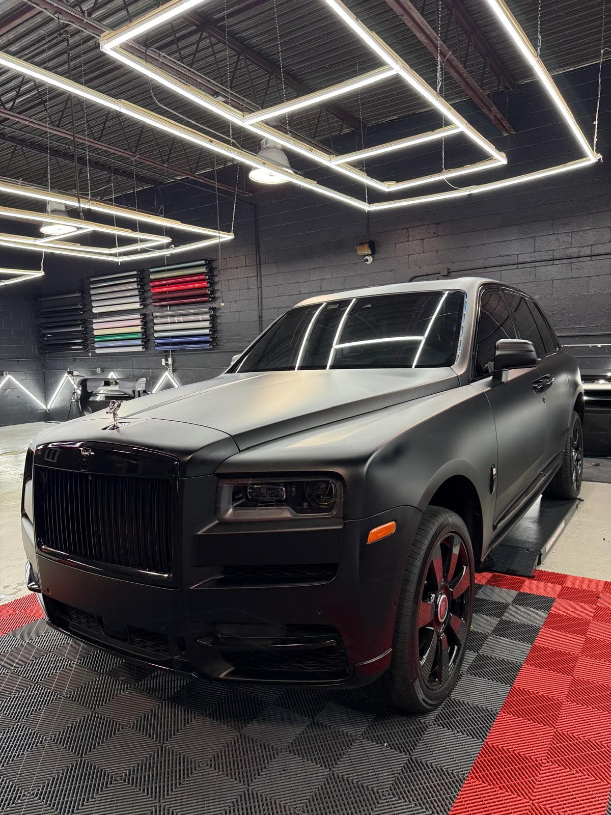 Satin black Rolls-Royce Cullinan, front three-quarter view, in a brightly lit garage