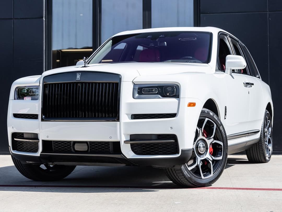 White Rolls-Royce Cullinan Black Badge with a dark grille and red interior, front three-quarter view